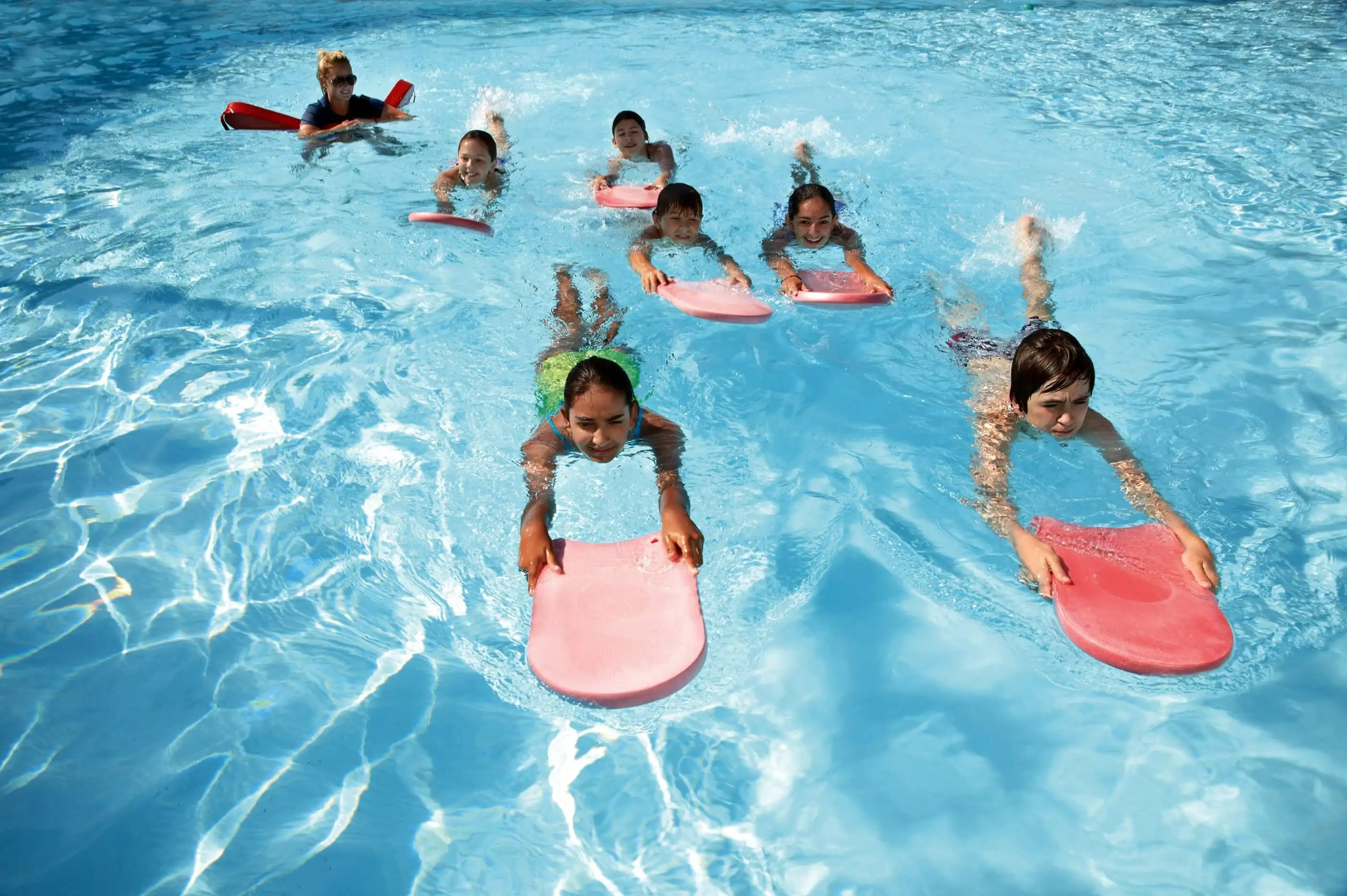 Swim instructor supporting a child at the edge of the pool during practice